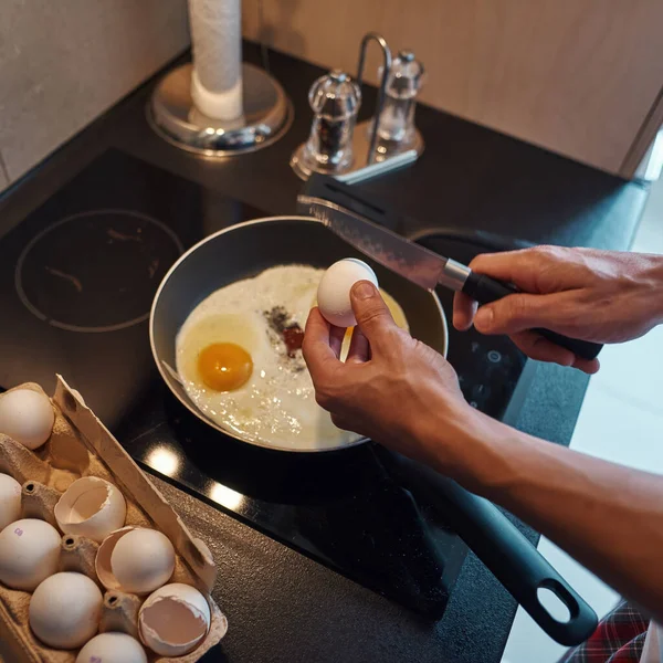 Вид сверху на человека, разбивающего яйцо ножом на сковороде — стоковое фото