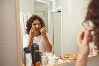 Genç Avrupalı adam diş ipiyle dişlerini fırçalıyor