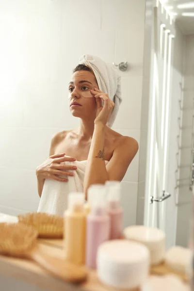 Woman apply under eye patches on face in bathroom — Fotografia de Stock