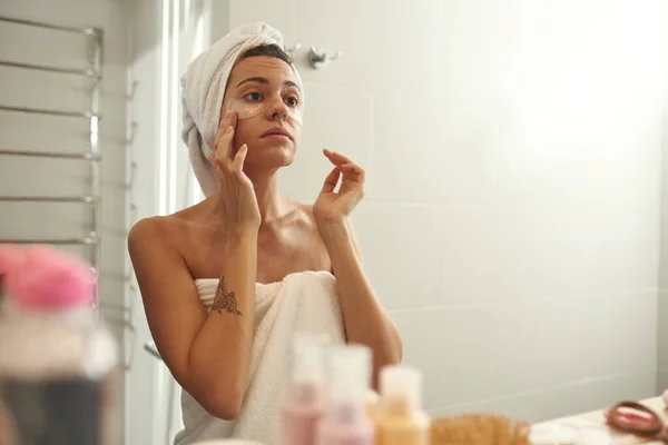 Woman looking at her face with under eye patches — Foto de Stock