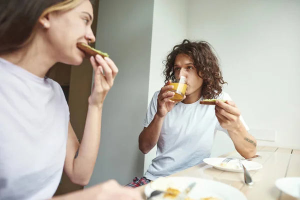 Caucasian couple eat sandwiches and drink juice — ストック写真