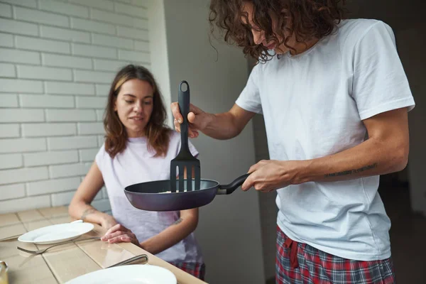Man putting fried eggs in plate of girlfriend — Foto Stock