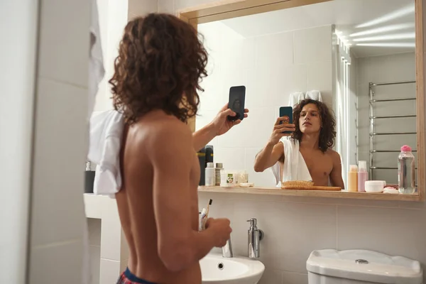 Людина фотографує себе в дзеркалі на смартфоні — стокове фото