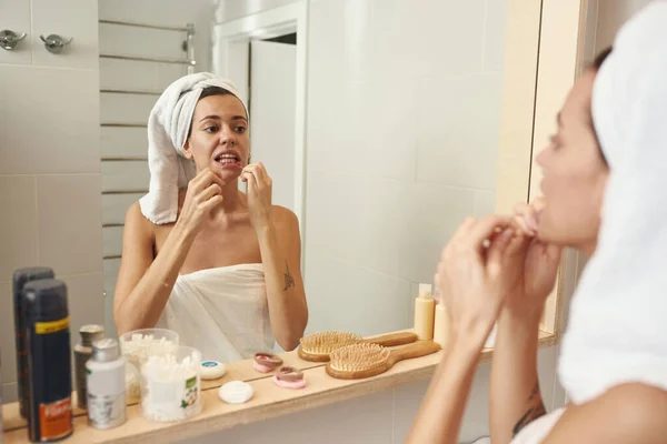 Mujer caucásica cepillándose los dientes con hilo dental — Foto de Stock