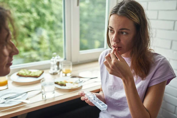 Girl taking pill after having breakfast with guy — ストック写真