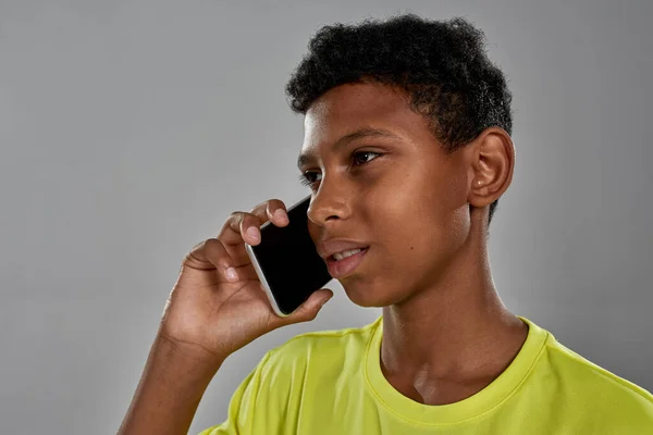 Концентрований спортивний чорний хлопчик говорить на смартфоні — стокове фото