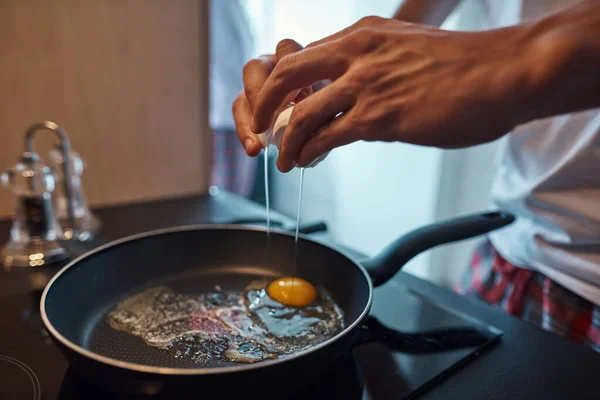 Man kastar trasiga ägg på stekpanna på elektrisk spis — Stockfoto