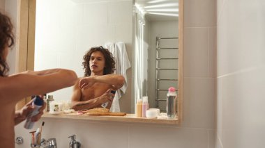 Adam banyoda koltukaltına terleme önleyici sürüyor.