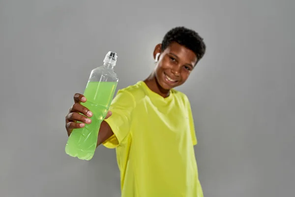 Smiling athletic black boy show green sport drink — Stock Photo, Image