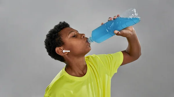 Чорний хлопчик п'є синій спортивний напій з пляшки — стокове фото