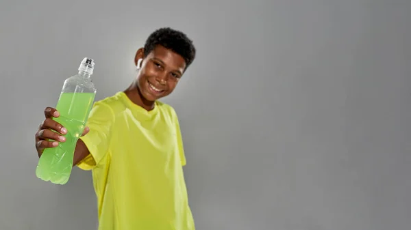 Mosolygó fekete fiú bemutató üveg sport ital — Stock Fotó