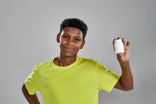 Sportive black boy showing jar with medical pills —  Fotos de Stock