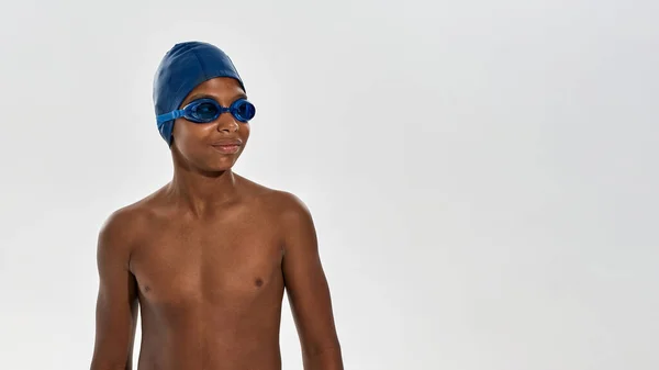 Обрізаний усміхнений чорний хлопчик плаває, дивлячись геть — стокове фото
