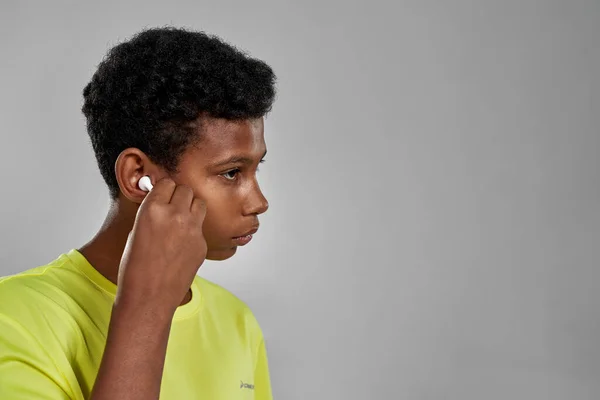 Siyahi bir çocuk kulağına kablosuz kulaklık takmış. — Stok fotoğraf