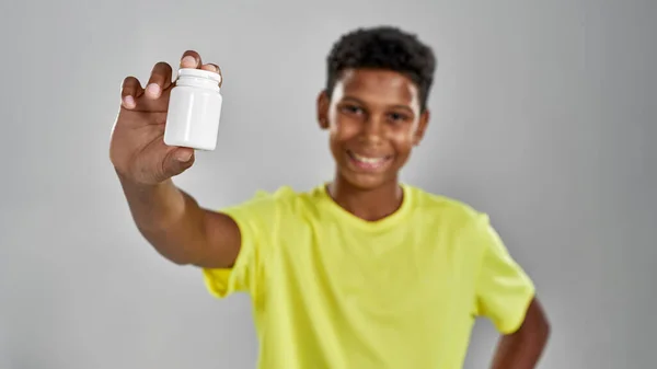 El foco del frasco con las pastillas en la mano del muchacho negro borroso — Foto de Stock