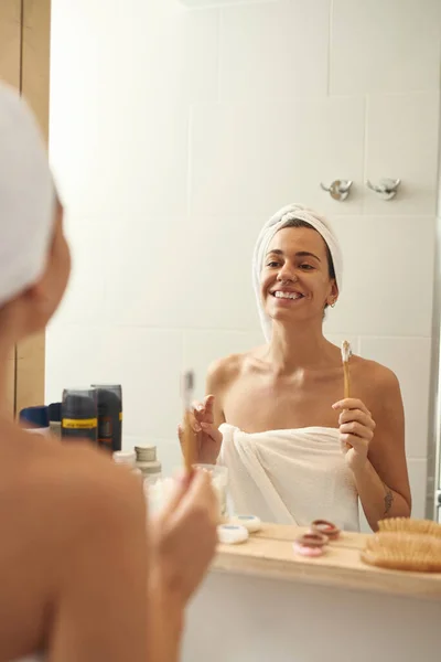 Woman with toothbrush look at mirror in bathroom — Fotografia de Stock