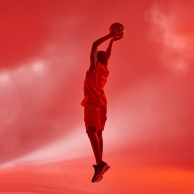 Zenci çocuğun sırtı zıplayıp basketbol topu atıyor.