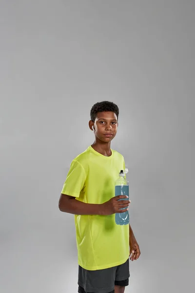 Niño negro deportivo con botella de bebida deportiva azul — Foto de Stock