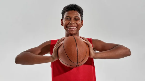 Mosolygó fekete fiú kosárlabda játékos kezében labda — Stock Fotó