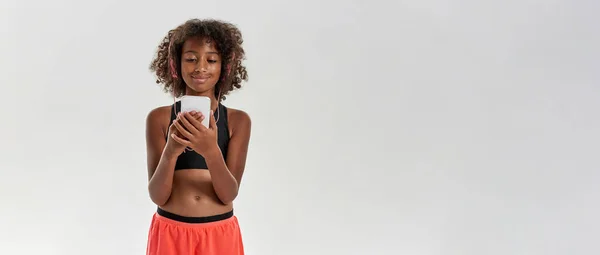 Smiling girl wear earphones watch on smartphone — Foto Stock