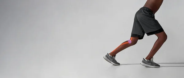 Run black boy with medical plasters on injured leg — Fotografia de Stock
