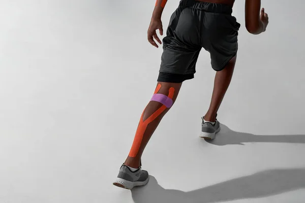 Correndo menino preto com emplastros na perna ferida — Fotografia de Stock