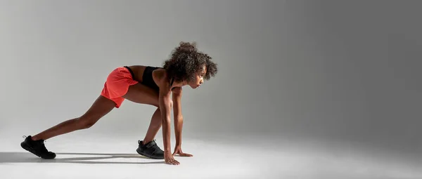 Focused black girl waiting on start before run — Stockfoto