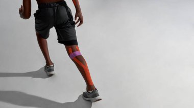 Bacağında yara bandı olan koşan zenci çocuk.