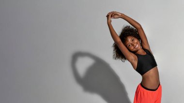 Atletik siyah kız ısınıyor ve kameraya bakıyor.