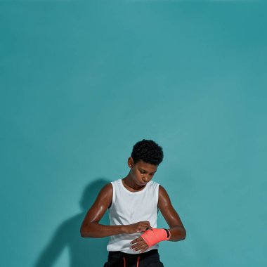 Odaklanmış çocuk boksör boks bandajını elinde tutuyor.