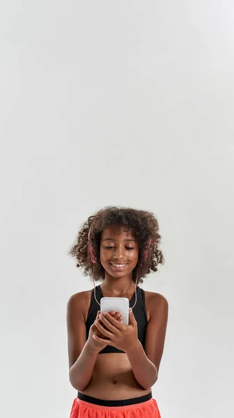 Sport fekete lány visel fülhallgató használata okostelefon — Stock Fotó