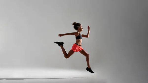 Odaklanmış atletik siyah kızın koşuşunun yan görüntüsü — Stok fotoğraf