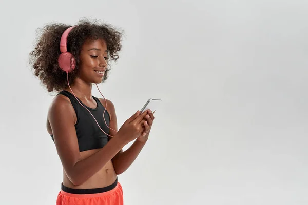 Sports black girl wear earphones browse smartphone — Foto de Stock