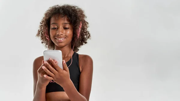 Smiling black girl wear earphones use smartphone — Foto Stock