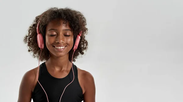 Pleased black girl listening music in earphones — Foto de Stock