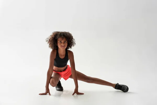 Svart flicka stretching ben och tittar på kameran — Stockfoto