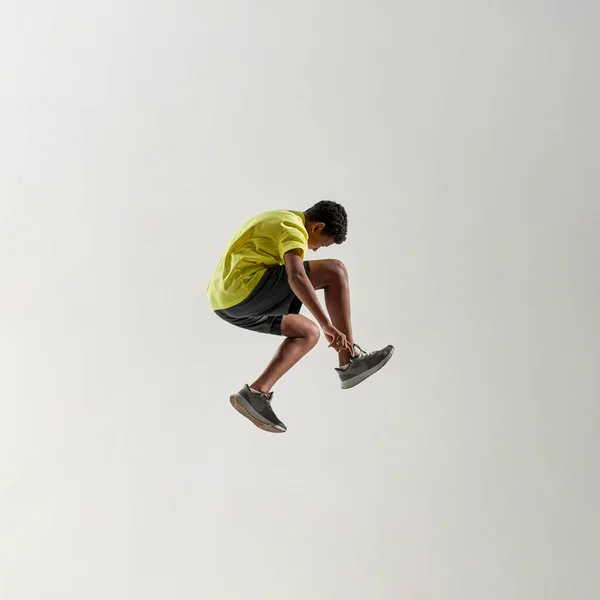 Side view of athletic black boy jump during run — Fotografia de Stock