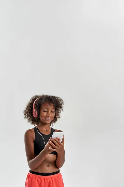 Black girl wear earphones watch on mobile phone — Foto Stock