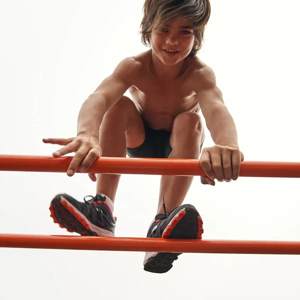 Bottom view of sports boy going on horizontal bar — Foto de Stock