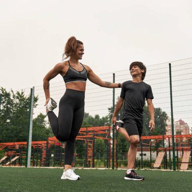 Gülen atletik anne ve oğlu bacak esnetiyorlar