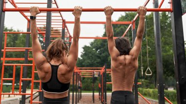 Anne ve oğlu yatay çubukta egzersiz yapıyor.