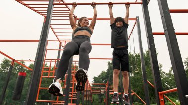 Atletik anne ve oğul yatay çizgide dururlar.