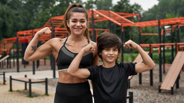 Neşeli atletik anne ve oğlu pazılarını gösteriyor.