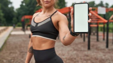 Focus on smartphone in hand of blurred sportswoman