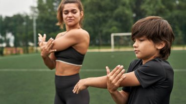 Anne ve oğlu spor sahasında ellerini ısıtıyorlar.