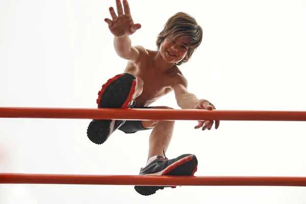 Sports boy go on horizontal bar on sports ground — Fotografia de Stock