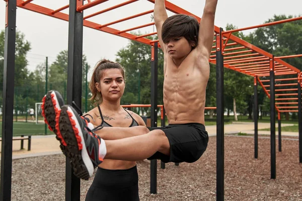 Caucasian athletic mother helping son doing abs — Foto de Stock