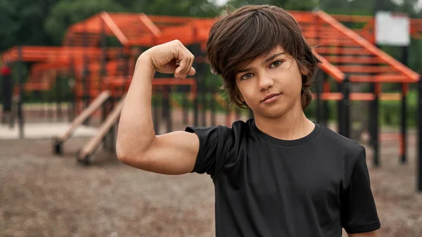 Sport pojke som visar biceps och tittar på kameran — Stockfoto
