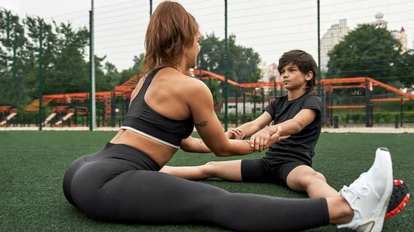 Athletic mother and son warm up on athletic field — Foto de Stock