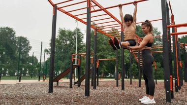 Yatay çubukta karın kaslarını çalıştıran bir kadın.